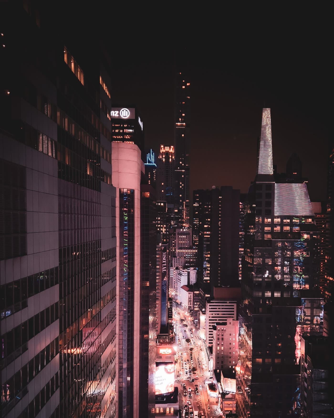 Illuminated skyscrapers and a busy avenue seen from above at night